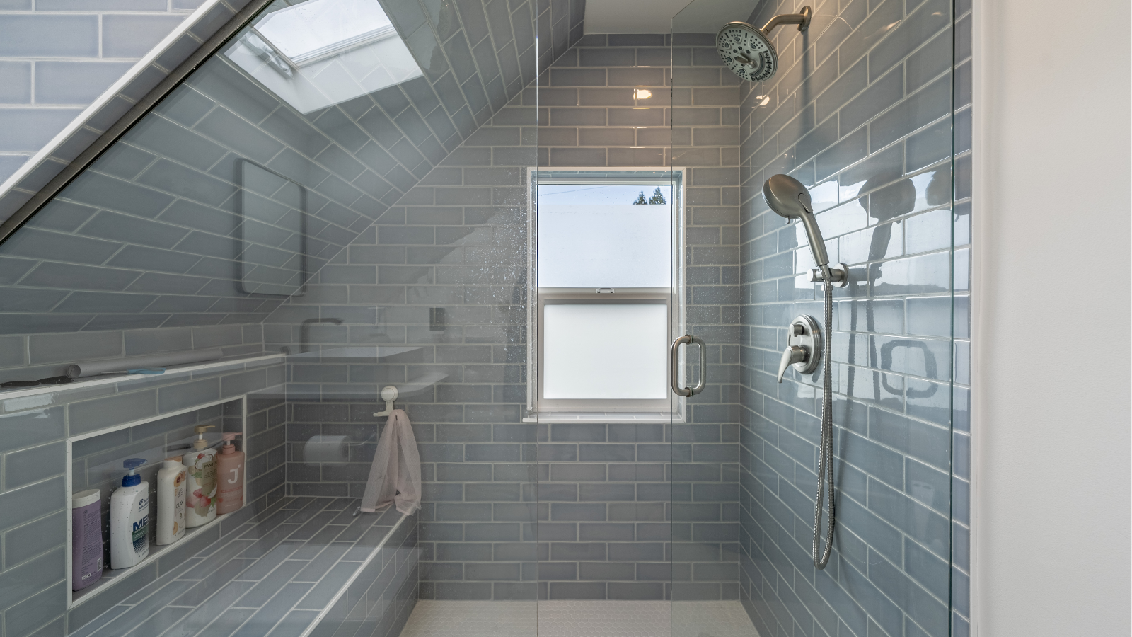 Attic bathroom remodel with light blue subway tile walk-in shower, skylight, and built-in bench.
